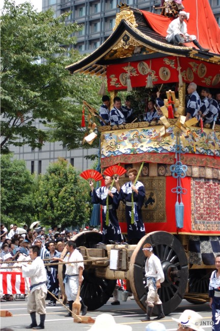 Priests ride a massive portable shrine on wheels in a parade for the Gion Festival in Kyoto. This is a popular Japanese summer matsuri festival.
