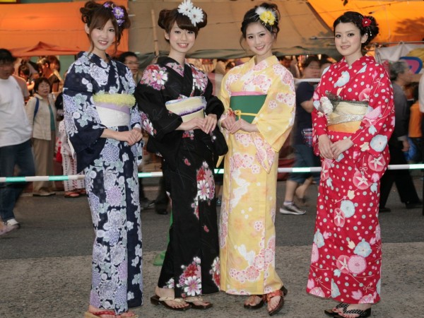 Four Japanese girls wearing colourful traditional yukata robes like a summer cotton version of a kimono at a summer matsuri festival
